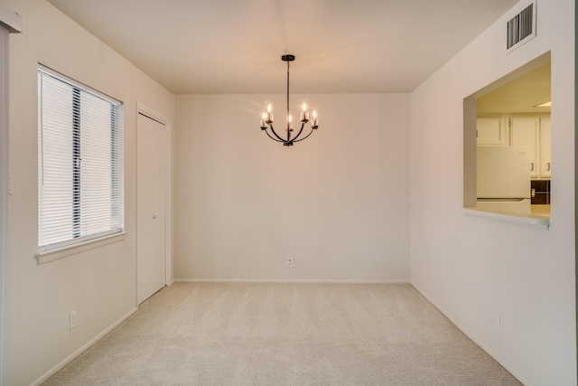 carpeted empty room featuring visible vents, baseboards, and a chandelier