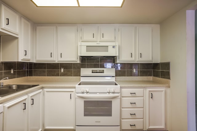 kitchen with white appliances, white cabinets, and a sink