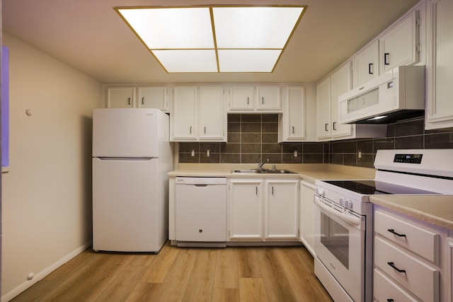 kitchen featuring a sink, light wood finished floors, white appliances, light countertops, and backsplash