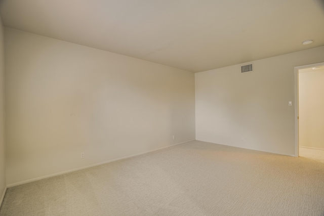 unfurnished room featuring baseboards, light colored carpet, and visible vents