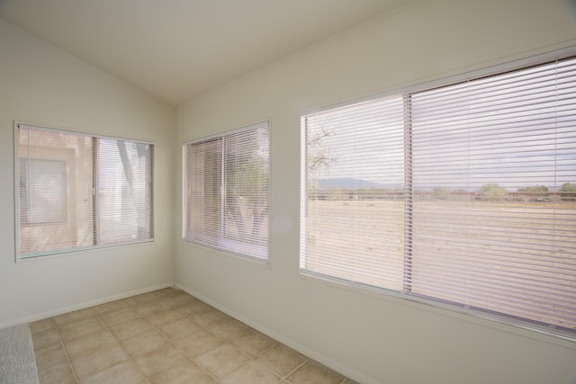 spare room featuring baseboards and lofted ceiling