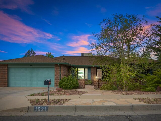 single story home featuring a garage, driveway, and brick siding