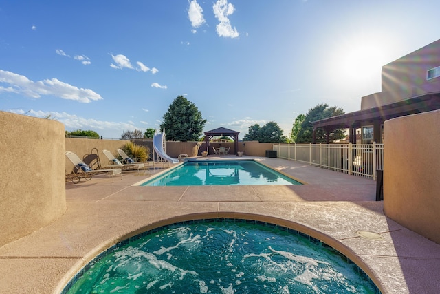 view of swimming pool with a gazebo, a patio area, fence, an in ground hot tub, and a water slide