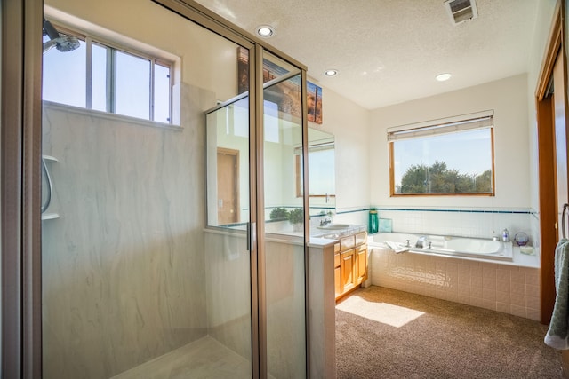 full bathroom featuring a shower stall, a garden tub, visible vents, vanity, and a textured ceiling