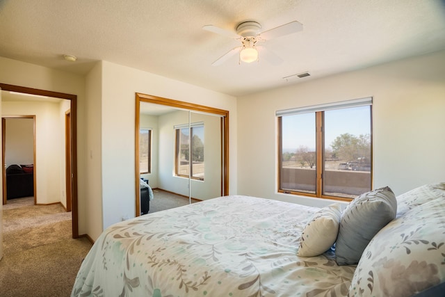 carpeted bedroom featuring baseboards, visible vents, a closet, and ceiling fan