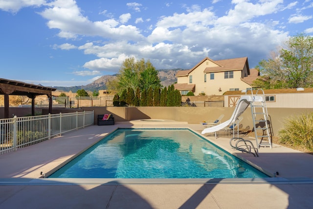 view of pool with a patio area, a mountain view, fence, a fenced in pool, and a water slide