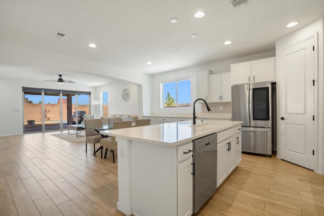 3003 Turquesa SE, Rio Rancho, NM 87124 - kitchen featuring stainless steel appliances, open floor plan, light countertops, light wood-style floors, and an island with sink
