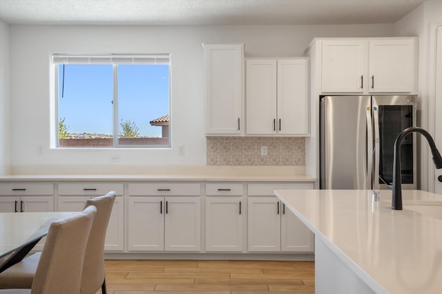 3003 Turquesa SE, Rio Rancho, NM 87124 - kitchen featuring smart refrigerator, white cabinetry, light wood-type flooring, light countertops, and tasteful backsplash