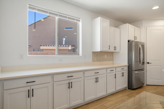 3003 Turquesa SE, Rio Rancho, NM 87124 - kitchen with freestanding refrigerator, light wood-style flooring, white cabinets, decorative backsplash, and recessed lighting