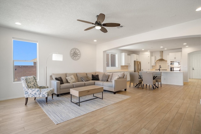 3003 Turquesa SE, Rio Rancho, NM 87124 - living area with light wood-style flooring, ceiling fan, arched walkways, a textured ceiling, and recessed lighting