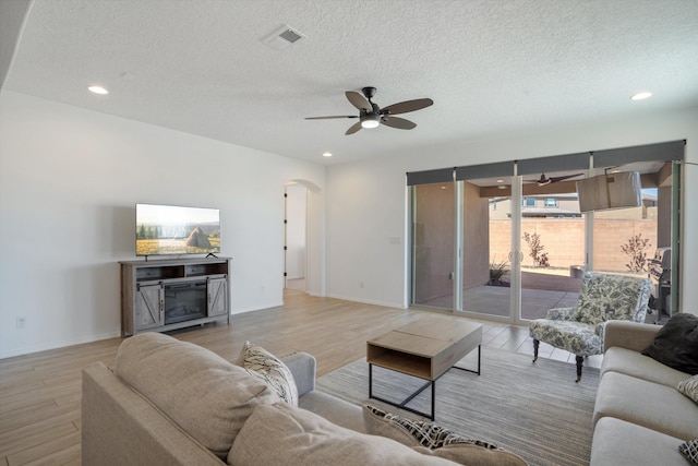 3003 Turquesa SE, Rio Rancho, NM 87124 - living room featuring ceiling fan, arched walkways, light wood-type flooring, a textured ceiling, and baseboards
