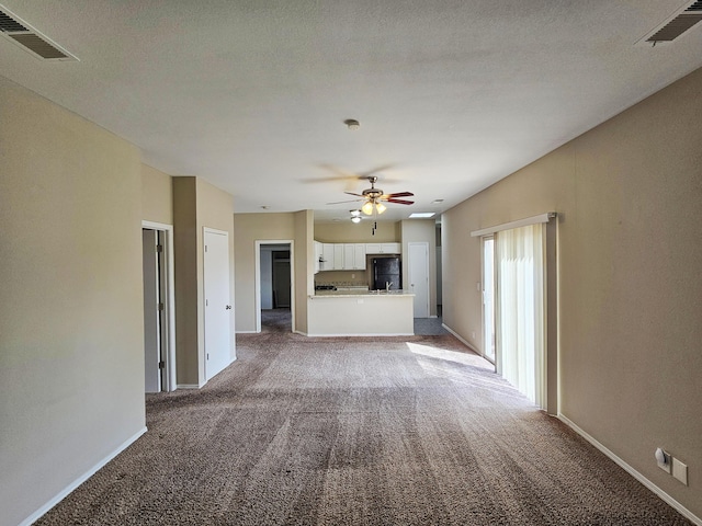 unfurnished living room featuring baseboards, visible vents, light colored carpet, and ceiling fan