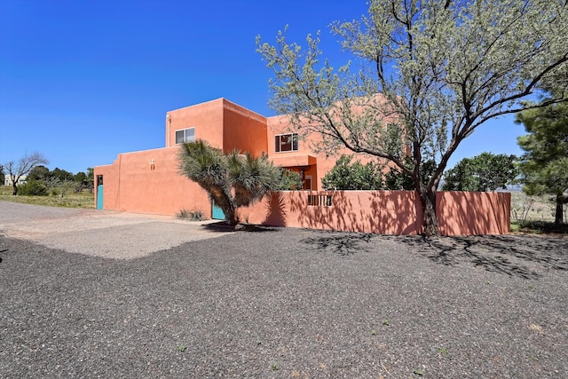 view of side of home featuring fence and stucco siding