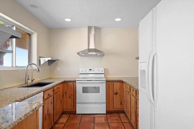 kitchen with wall chimney range hood, a textured ceiling, a sink, recessed lighting, and white appliances
