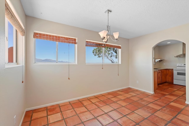 unfurnished room featuring a textured ceiling, arched walkways, light tile patterned floors, baseboards, and an inviting chandelier