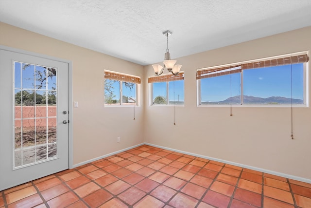 unfurnished dining area featuring baseboards, a textured ceiling, light tile patterned floors, and a notable chandelier