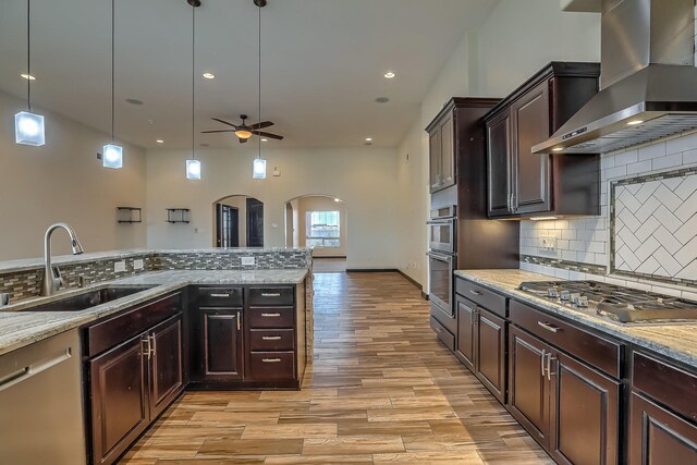 1797 Vargas Rd SE, Rio Rancho, NM 87124 - kitchen with wall chimney exhaust hood, appliances with stainless steel finishes, arched walkways, ceiling fan, and light wood-type flooring