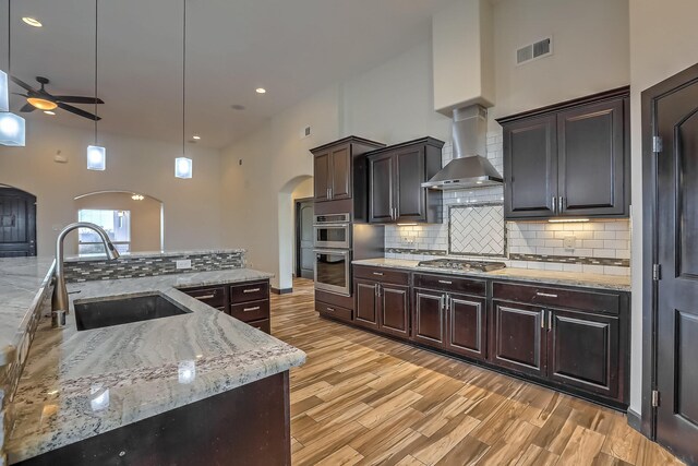 1797 Vargas Rd SE, Rio Rancho, NM 87124 - kitchen featuring arched walkways, ceiling fan, a towering ceiling, appliances with stainless steel finishes, and wall chimney exhaust hood