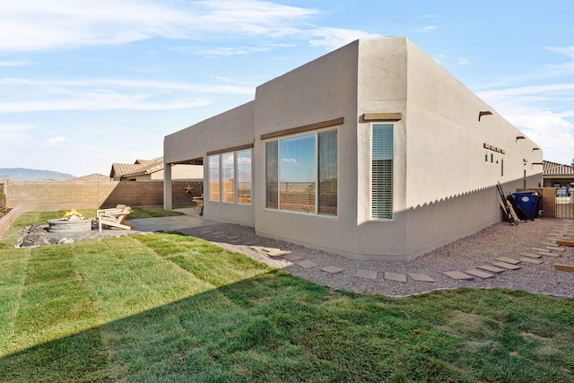 9109 Retablo Rd NW, Albuquerque, NM 87120 - view of home's exterior featuring a lawn, a fenced backyard, a fire pit, and stucco siding