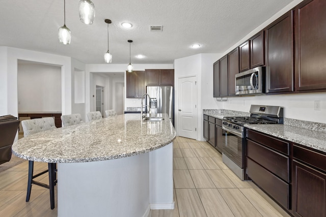 9109 Retablo Rd NW, Albuquerque, NM 87120 - kitchen with a kitchen breakfast bar, dark brown cabinets, visible vents, pendant lighting, and appliances with stainless steel finishes