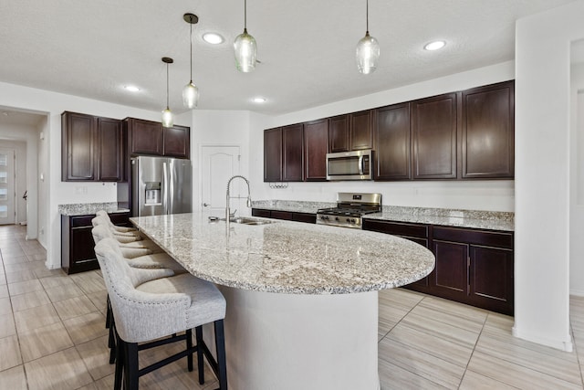 9109 Retablo Rd NW, Albuquerque, NM 87120 - kitchen featuring a sink, dark brown cabinetry, pendant lighting, appliances with stainless steel finishes, and a breakfast bar area