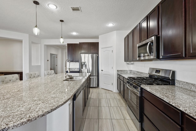 9109 Retablo Rd NW, Albuquerque, NM 87120 - kitchen featuring stainless steel appliances, dark brown cabinets, visible vents, a sink, and pendant lighting