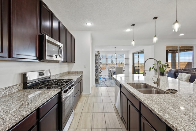 9109 Retablo Rd NW, Albuquerque, NM 87120 - kitchen with light stone counters, hanging light fixtures, stainless steel appliances, and a sink