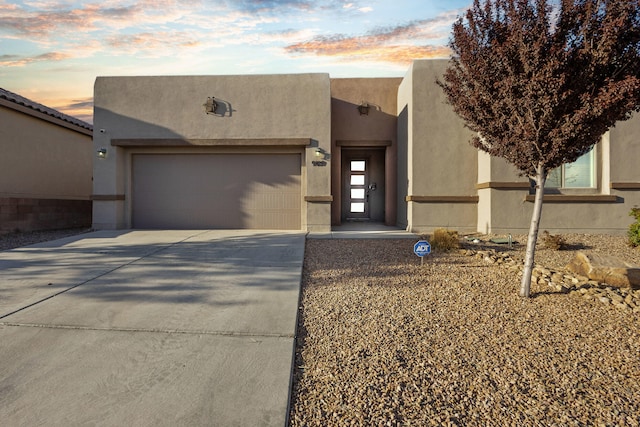 9109 Retablo Rd NW, Albuquerque, NM 87120 - pueblo-style home with an attached garage, stucco siding, and driveway