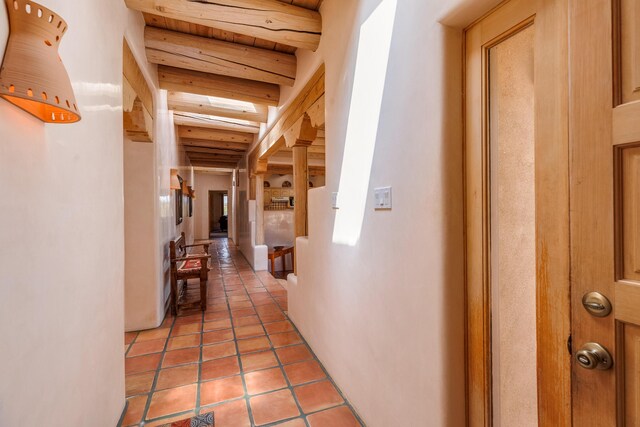 corridor featuring beamed ceiling, wooden ceiling, and light tile patterned flooring