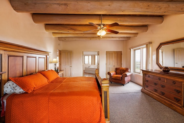 carpeted bedroom featuring ceiling fan, beam ceiling, and ensuite bathroom