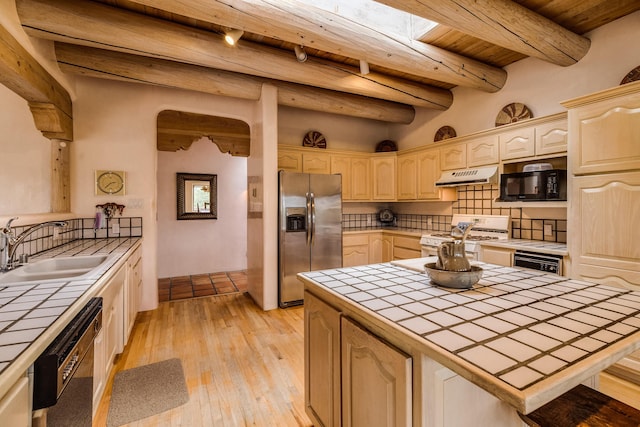 kitchen featuring tile counters, a sink, black appliances, wood ceiling, and under cabinet range hood