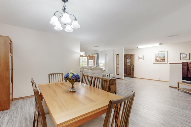 dining area featuring light wood-style floors, visible vents, baseboards, and a notable chandelier