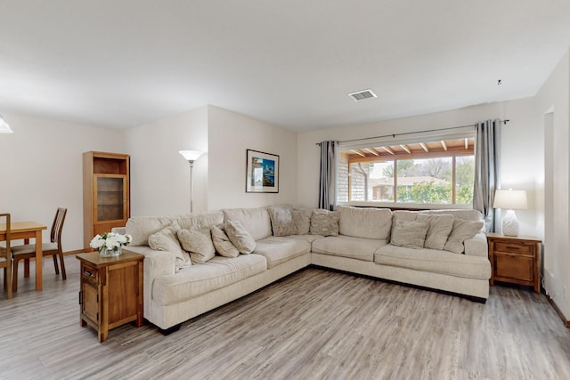 living area featuring baseboards, light wood-style flooring, and visible vents