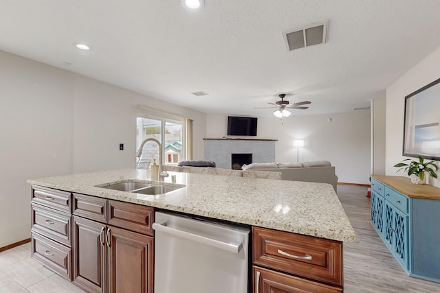 kitchen featuring stainless steel dishwasher, a ceiling fan, a sink, a center island with sink, and visible vents