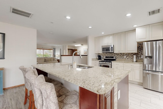 kitchen with light stone countertops, visible vents, a sink, and appliances with stainless steel finishes