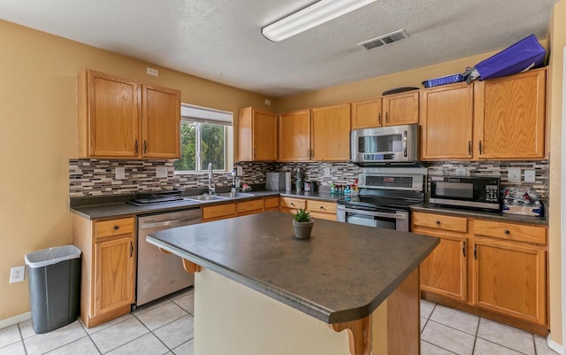 7419 Tolleson Ave NW, Albuquerque, NM 87114 - kitchen with stainless steel appliances, dark countertops, visible vents, a sink, and light tile patterned flooring
