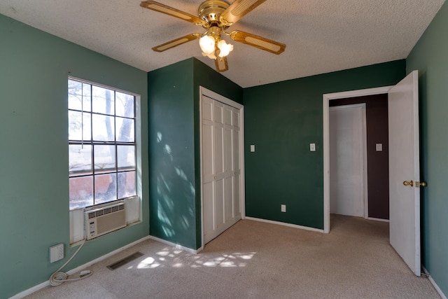 unfurnished bedroom featuring multiple windows, cooling unit, a textured ceiling, and carpet flooring