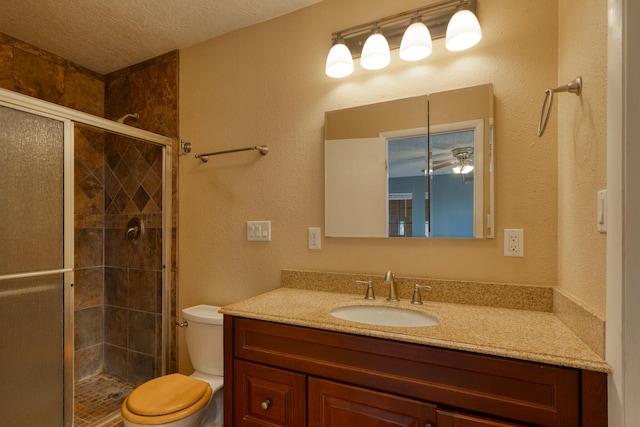 bathroom featuring toilet, a shower stall, a textured ceiling, vanity, and ceiling fan