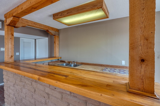 kitchen with baseboards, a sink, and a textured ceiling