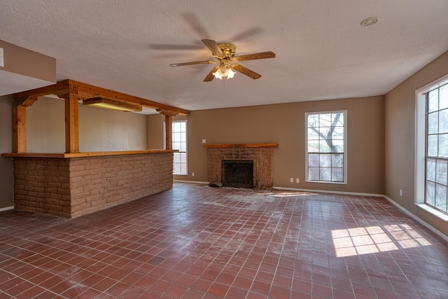unfurnished living room featuring healthy amount of natural light, a ceiling fan, a textured ceiling, baseboards, and a fireplace