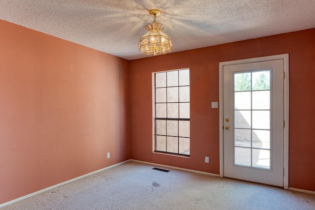 entryway with a chandelier, carpet floors, a textured ceiling, and baseboards