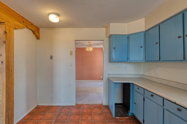 kitchen with blue cabinets, dark tile patterned flooring, light countertops, and baseboards