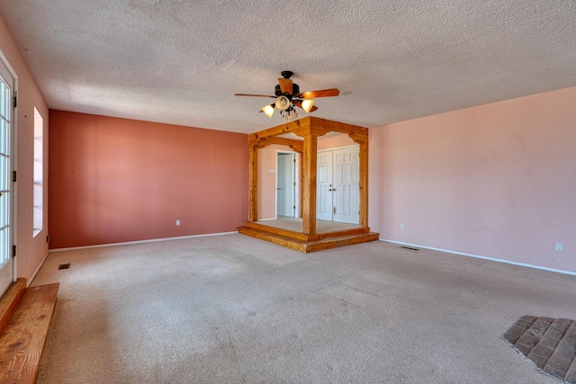 unfurnished room featuring carpet floors, ceiling fan, baseboards, and a textured ceiling