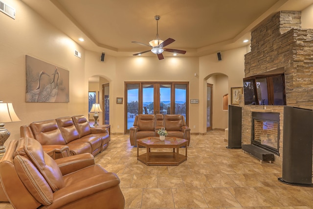 255 Diamond Tail Rd, Placitas, NM 87043 - living room with arched walkways, a fireplace, ceiling fan, a towering ceiling, and a tray ceiling