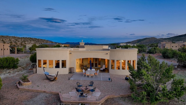 rear view of property with stucco siding, a chimney, a patio area, and a mountain view