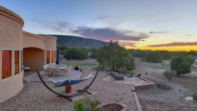 255 Diamond Tail Rd, Placitas, NM 87043 - yard at dusk featuring an outdoor fire pit, a patio area, and a mountain view
