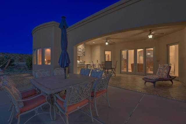 255 Diamond Tail Rd, Placitas, NM 87043 - patio at night featuring outdoor dining area, ceiling fan, a patio, french doors, and an outdoor kitchen