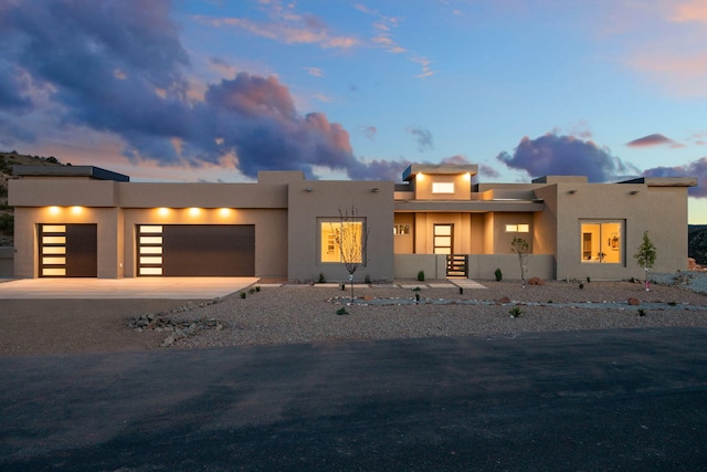 pueblo-style house with a garage, stucco siding, and concrete driveway