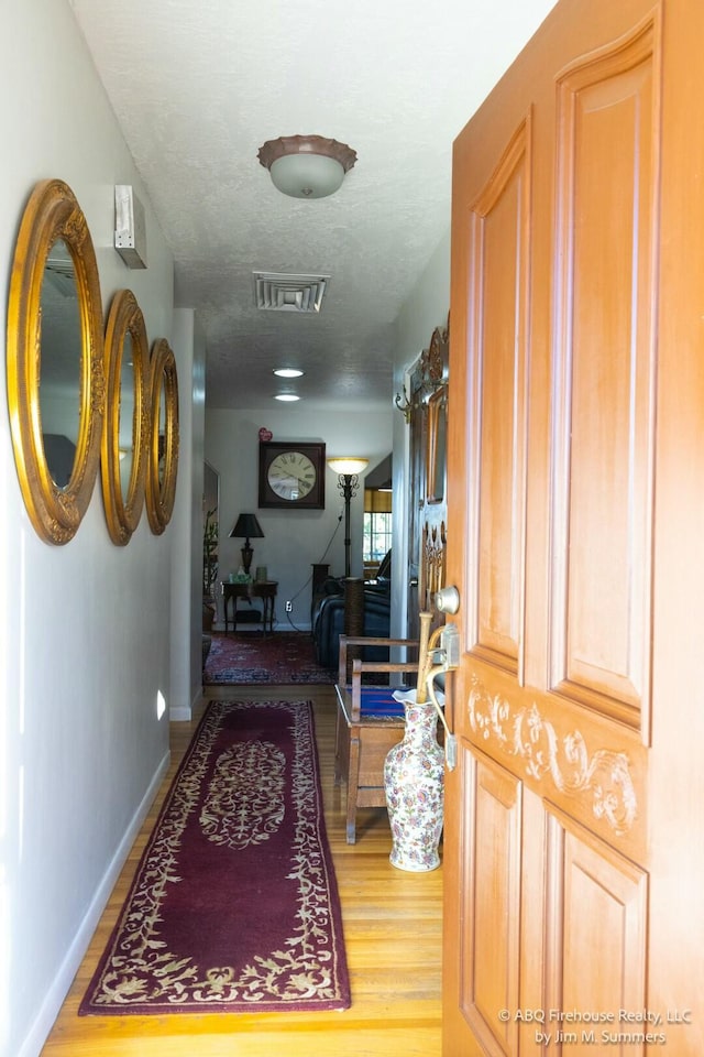 hallway with visible vents and wood finished floors