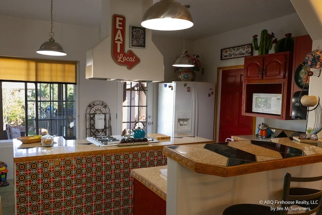 kitchen with white fridge with ice dispenser, pendant lighting, a peninsula, and tile counters
